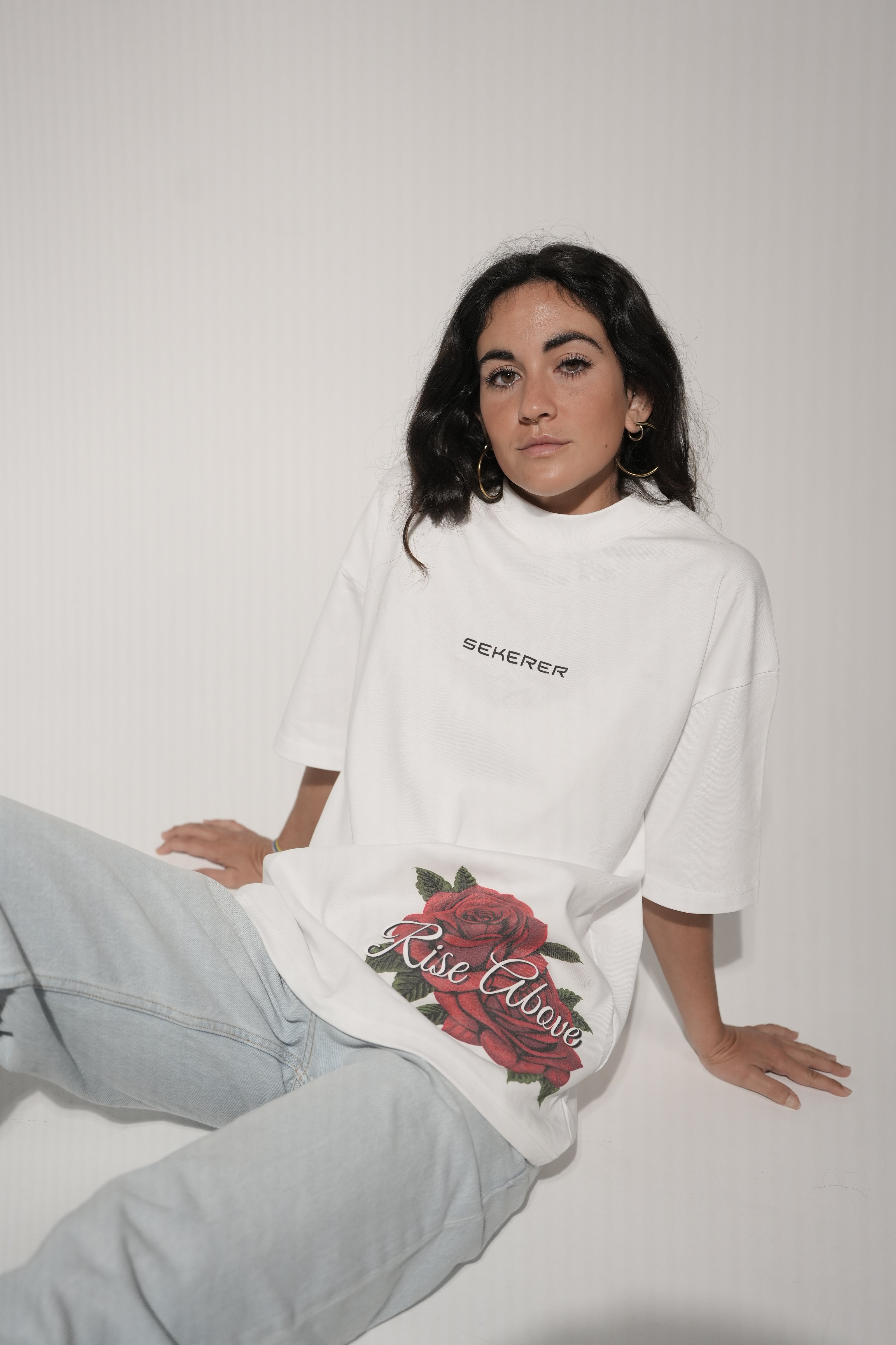 Female model wearing Ascend Rose oversized white t-shirt with rose graphic detail by Sekerer