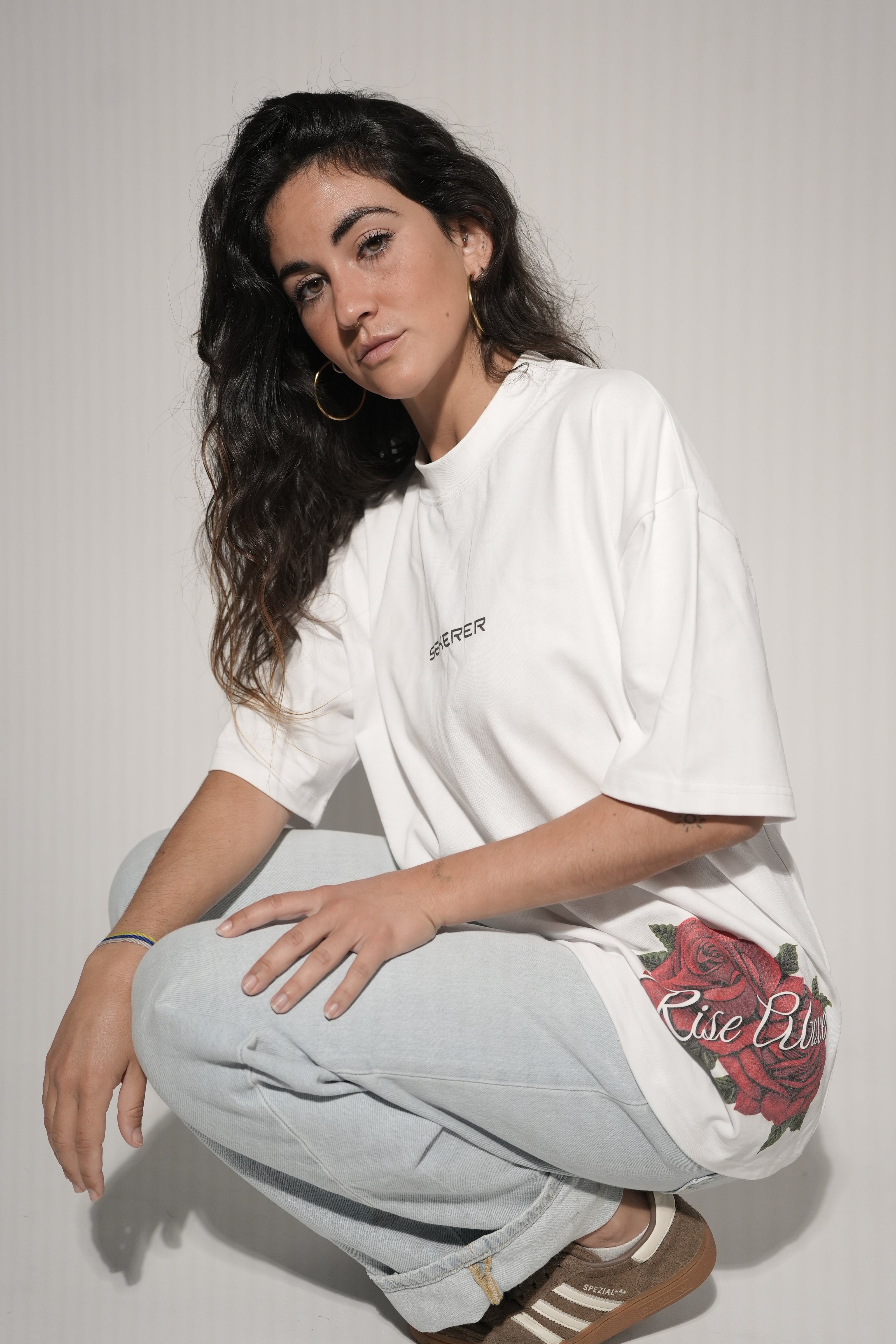 Female model showcasing Ascend Rose oversized white t-shirt with rose print by Sekerer